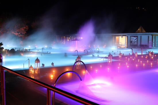 Sur le fond le bassin, sa vapeur bleutée et mauve. Sur le bord plusieurs lanternes et bougies allumées, enveloppées d'une lueur rose et mauve