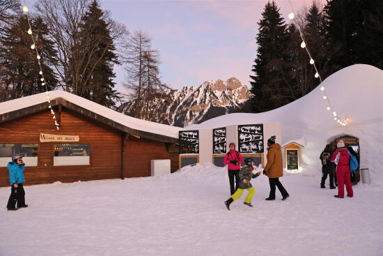 Group of people waiting at the entrance to an igloo and children running with a view of the Grand Chamossaire