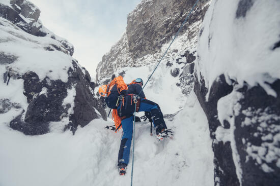 Homme encordé grimpant une paroi enneigée avec le Bureau des guides des Alpes Vaudoises