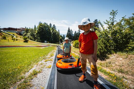 Enfants remontant avec leurs bouées sur la tapis du tubing au Villars Fun Park