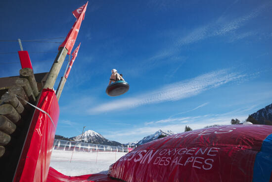 Person in the air on a buoy after taking a Tobogganing jump before landing on a big air bag