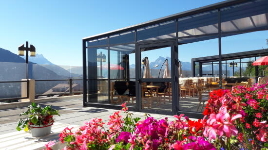 Photo de la terrasse du restaurant le Bel Air avec fleures colorées et vu sur les montagnes