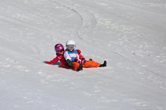 Deux enfants sur une luge descendent une piste enneigée
