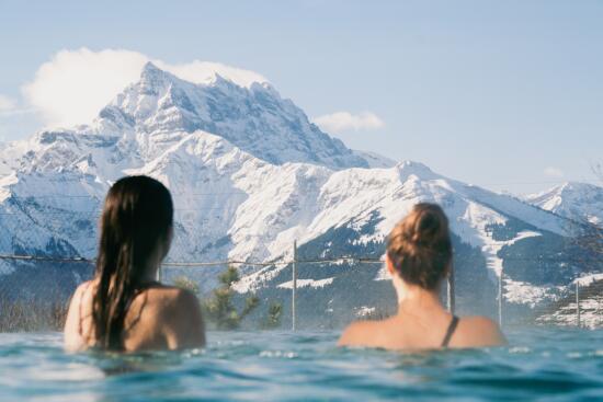 Femmes de dos dans le bassin chaud des Bains de Villars, regardant le paysage, Dents du Midi.