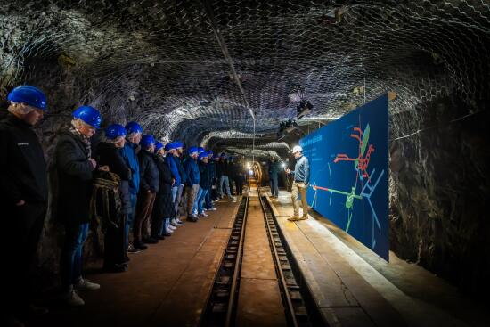 Un groupe se tient près des rails et écoute les explications du guide lors de la visite des mines de sel.